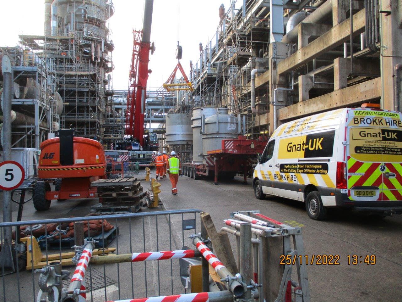 GNAT UK Brokk Hire mobilisation on a live COMAH-regulated refinery site — JLG access platform, scaffolding, crane lifting a process vessel, hi-vis operator and the GNAT UK fleet van staged in the foreground