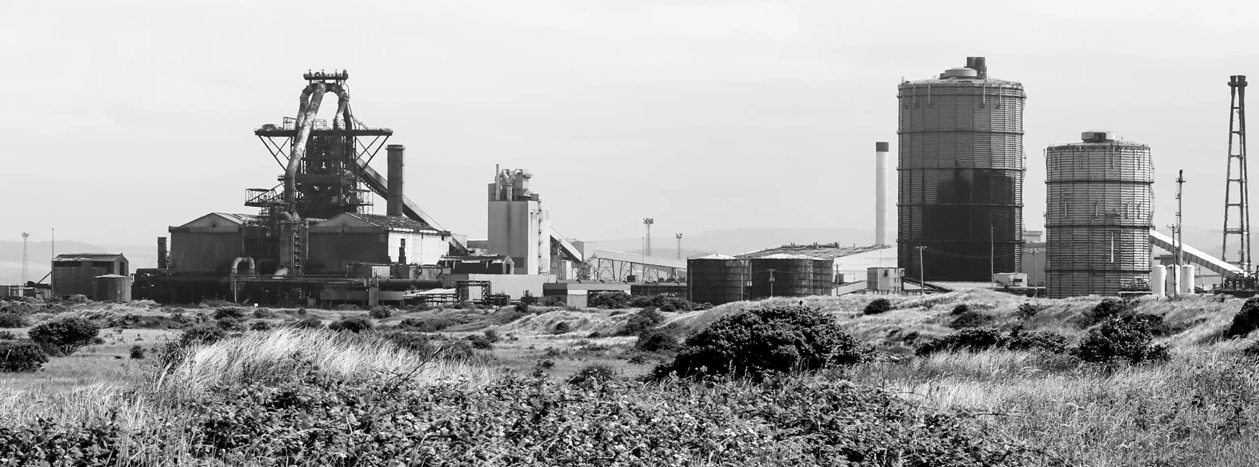 Wide black-and-white view of a British Steel works — blast furnace and process plant infrastructure on the Teesside skyline, the scale of UK heavy-industrial refractory and process work GNAT UK operates in