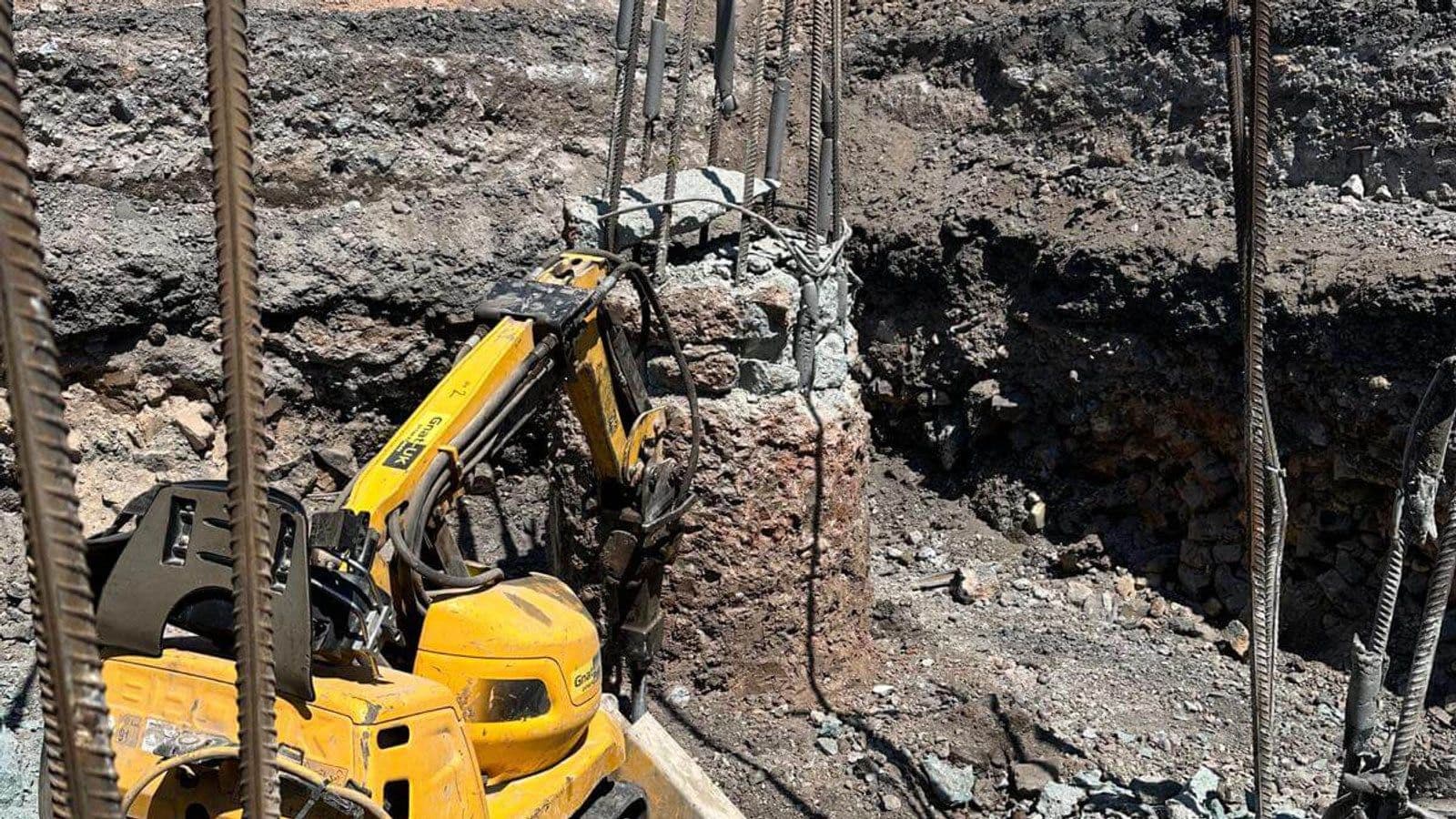 Brokk 60 robot pecking concrete from a pile head to expose the rebar inside a foundation pit