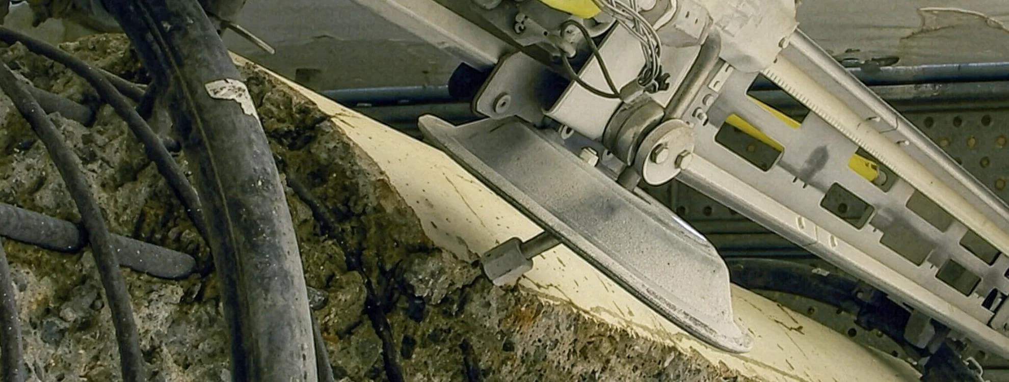 NALTA remote-controlled hydrodemolition lance close-up — the oscillating head working a concrete surface in a petrochemical environment